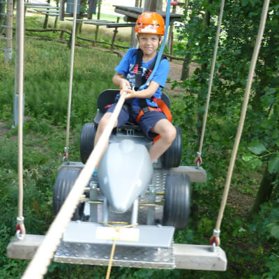 Ein Junge zieht sich auf einem Auto mit einem Seil ber die Kinderseilbahn